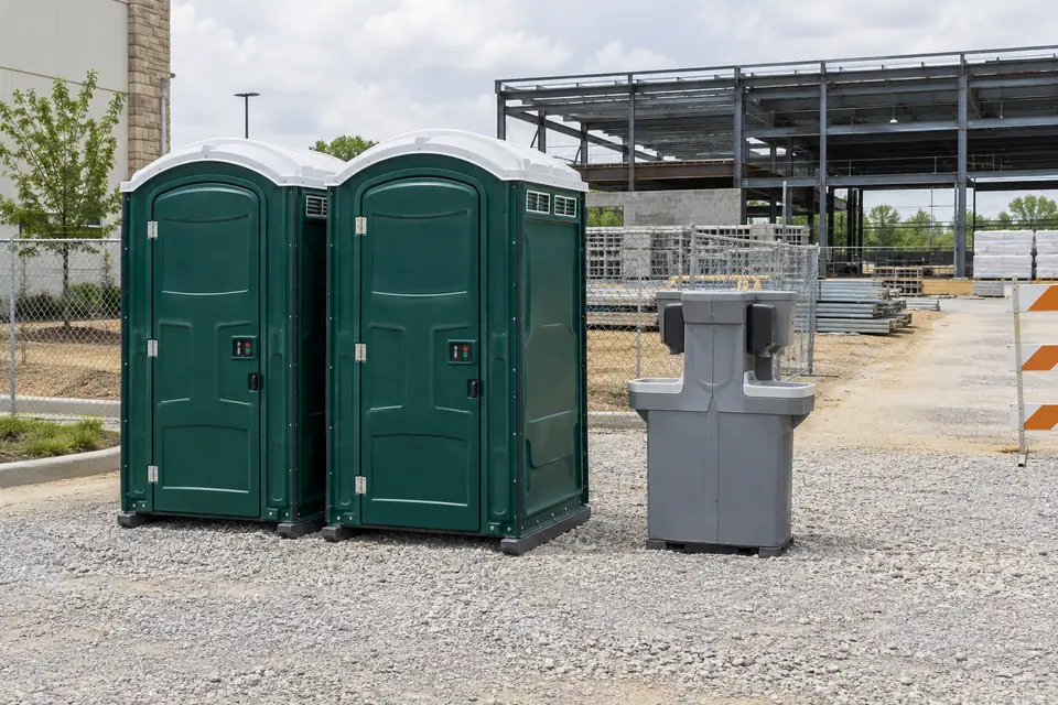 Portable toilets and handwashing equipment beside a construction work area